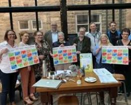 A group of people holding up their research findings (statements on sticky notes) at a training session