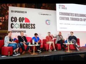 Co-op congress speakers on stage seated on chairs in a panel discussion